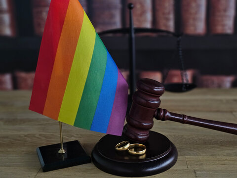 The rainbow flag, gavel, and wedding rings symbolize love and equality in the legal sphere. Divorce for LGBT couples concept