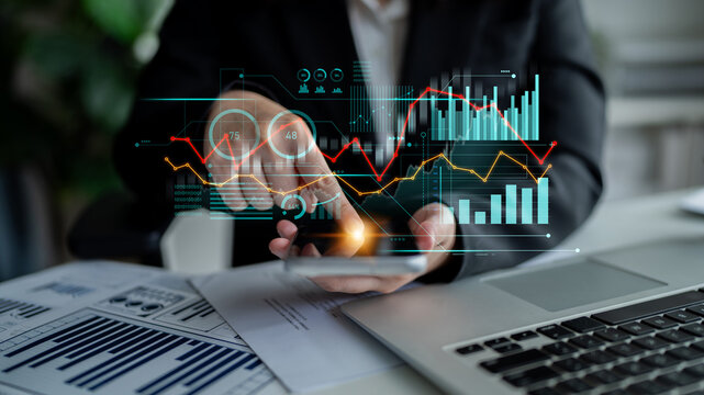 A business professional engages with a smartphone displaying futuristic data visualizations, symbolizing analysis and financial insights in a modern workspace. Scalp