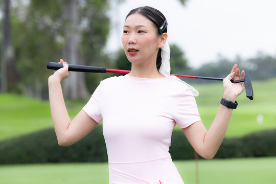 Asian woman golfer holding putter golf club at the green golf course, Asian woman play golf, Asian amateur golf woman player at golf course with putter.