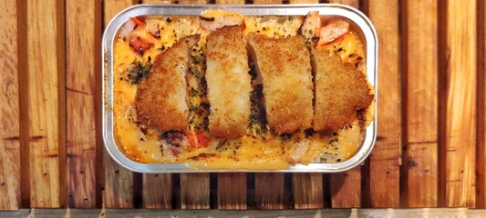 Crispy Chicken Katsu with Japanese Rice Mentai Sauce Served in a Alumunium Foil Container on Wood Table. Culinary Business Concept. Food Photography Presentation