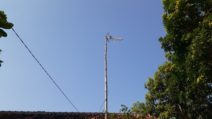 The television antenna is installed on the roof to get the best signal against the blue sky.