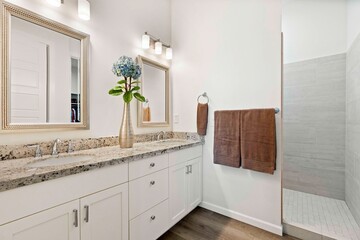 Spacious bathroom with two sinks, a large mirror, and walkin shower