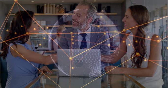 Discussing man in suit and women in sleeveless tops around glass table, with silver laptop hologram - Powered by Adobe