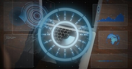 Displaying circular holographic UI on laptop keyboard at wooden desk, HUD panels, woman in dark top