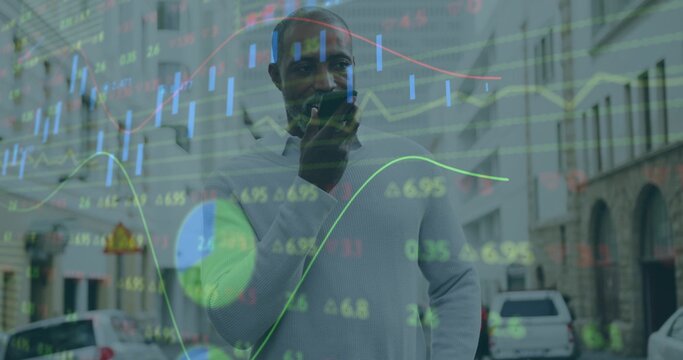 Standing man wearing light sweater holding device to mouth on city street with market charts - Powered by Adobe