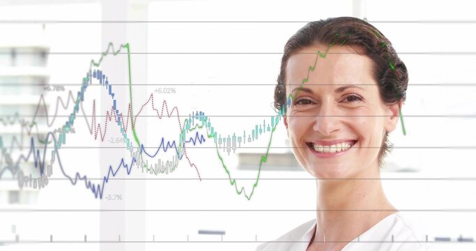 Smiling mid-adult woman in white top displaying financial charts at office windows, copy space