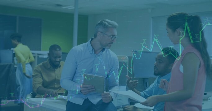 Talking man in light blue shirt sitting on desk holding tablet with financial chart at office - Powered by Adobe