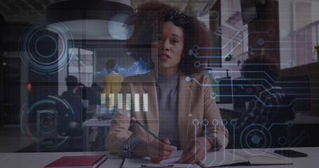 Writing woman in beige blazer addressing virtual presentation at open plan office, holographic UI