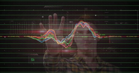 Adult male in plaid shirt reaching holographic chart in dark studio, with waveforms and green grid