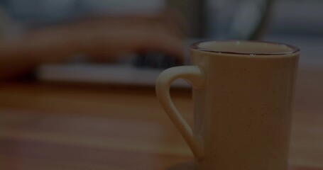Sitting speckled ceramic mug with handle facing left on wood table near laptop keyboard, copy space © vectorfusionart