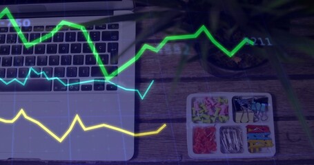 Displaying partial laptop keyboard, trackpad on left wooden desk with tray, plant, graph overlay