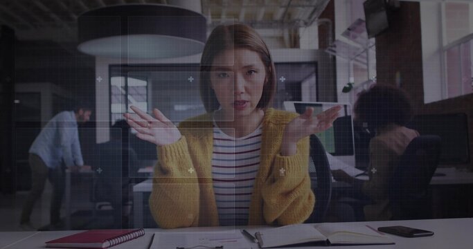 Gesturing woman wearing mustard cardigan explaining at modern office desk, with planner and phone - Powered by Adobe