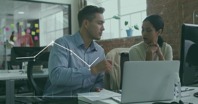 Discussing seated coworkers in light office attire at desk reviewing documents and data with laptop