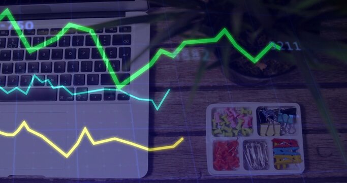 Displaying partial laptop keyboard, trackpad on left wooden desk with tray, plant, graph overlay
