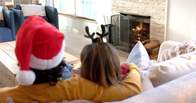 Fireplace flames crackling, couple resting on sofa, she sipping mug for warmth and laughing