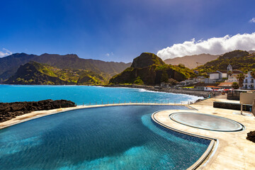 View of the rocky coast and the blue Atlantic ocean with waves on a beautiful sunny day in Madeira (Porto da Cruz), nature background or travel wallpaper 