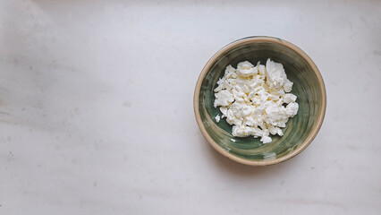 Homemade Cottage cheese in a ceramic bowl on the marble table, top view, copy space. Organic bio farm dairy product. Healthy eating concept.