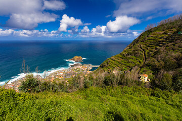 Dramatic Waves and Coastal Village Beneath Towering Cliffs, Madeira island, Portugal, background or travel wallpaper