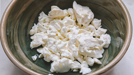 Close-up of Homemade Cottage cheese in a ceramic bowl on the marble table, top view, copy space. Organic bio farm dairy product. Healthy eating concept.