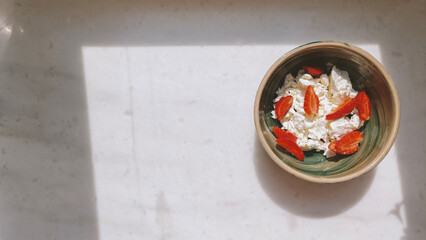 Homemade Cottage cheese with strawberries in a ceramic bowl on the marble table, top view, copy space. Organic bio farm dairy product. Healthy eating concept.