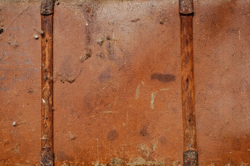 a weathered, brown leather suitcase with two vertical, rusted metal clasps. The leather surface is textured with visible scratches, scuffs, and small, irregular holes