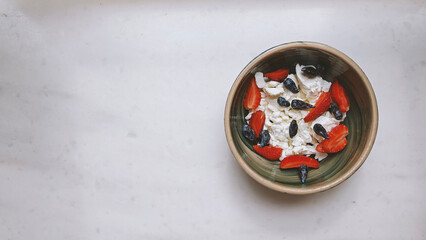 Homemade Cottage cheese with strawberries and honey berries in a ceramic bowl on the marble table,...
