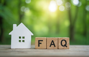 Wooden blocks form FAQ acronym near small house model. Concept illustrates common questions about real estate. Natural light with blur green forest background helps understand housing topics.