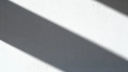 Diagonal shadow cast on a textured white wall