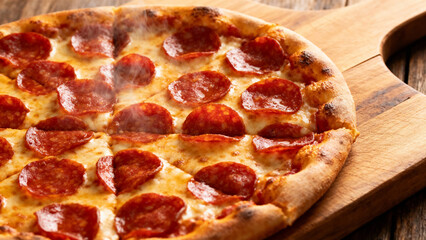 Freshly baked pepperoni pizza with melted cheese and crispy crust on a wooden cutting board