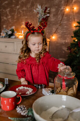 Little girl in a red dress preparing Christmas treats, baking in the kitchen, New Year holiday, Christmas
