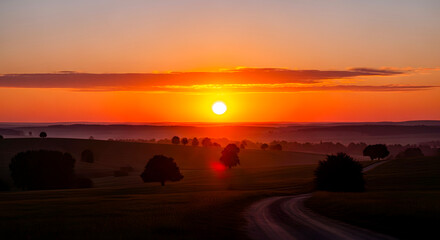 Sunset over a serene landscape with a winding road and trees