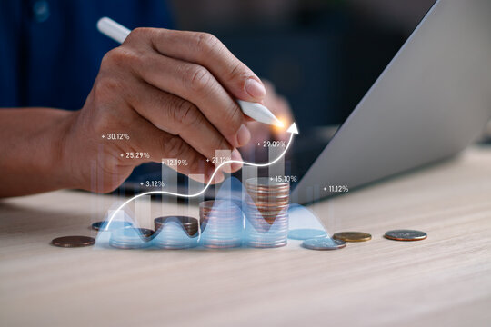Closeup of hand with stylus drawing on coin stack and financial graph. Concept of investment growth, wealth planning, finance analytics, ROI calculation and financial technology innovation