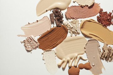 Set of different textures of cosmetic foundation, concealer, highlighter, soft powder, bronzer, on neutral grey beige background