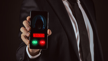 Business Man Holding a Smartphone Displaying a Critical Digital 'Warning' from an Unknown Hooded...