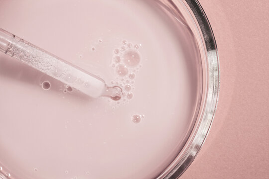 Liquid opaque pink milky gel with pipette on light pink colored background