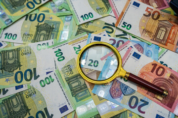 Euro banknotes with magnifier, money inspection, audit, fraud detection and financial control concept