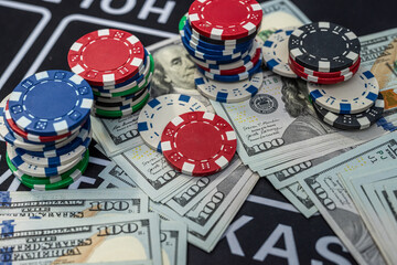 Colorful poker chips on stacks of US dollar bills symbolizing gambling, wealth, casino and betting concept
