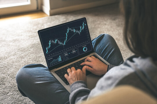 Trader Analyzing Live Financial Candlestick Charts and Investment Data on a Laptop Screen while Working Comfortably from Home