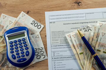 Blue calculator with PIT-37 tax form and 200 Polish zloty banknotes, personal finance and accounting concept