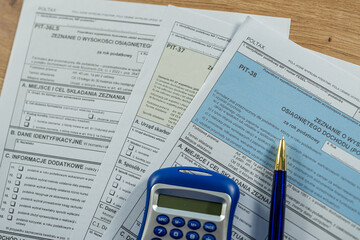 Polish PIT-11, PIT-37 and PIT-38 tax documents with blue calculator and 200 zloty bills, accounting concept
