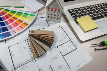 Laptop and wood laminate samples with colorful floor plan, interior design and renovation workspace