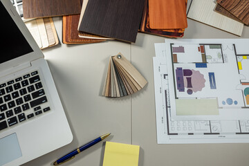 Interior designer workplace with laptop, house plan and wooden samples, home planning concept