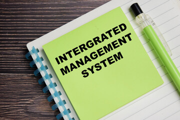 Concept of integrated management system write on sticky notes isolated on Wooden Table.