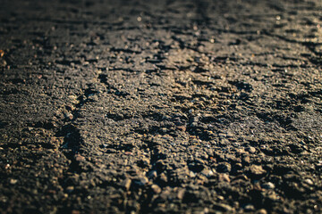 low angle close-up shot of a rough asphalt surface. texture, and natural wear patterns. infrastructure, ruggedness, and adversity. abstract background with copy space.