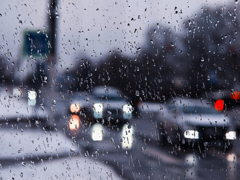City traffic through wet rainy window abstract backdrop