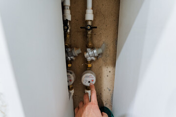 inspecting water meter with fingers, routine household water meter inspection and reading detailed view, closeup shot capturing manual process of checking and adjusting household water meters