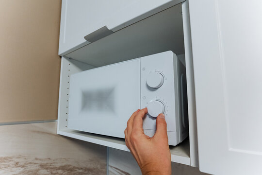 kitchen timer adjustment, person sets microwave cooking timer, individual adjusts microwave timer with tactile grip in kitchen, closeup view of hand turning microwave dial to set cooking duration