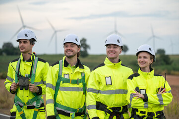 Team of engineers wearing safety helmets inspecting wind turbines at a wind farm, teamwork renewable energy.