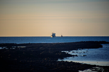 Fishing Boats on the Horizon at Rocky Iceland Coastline