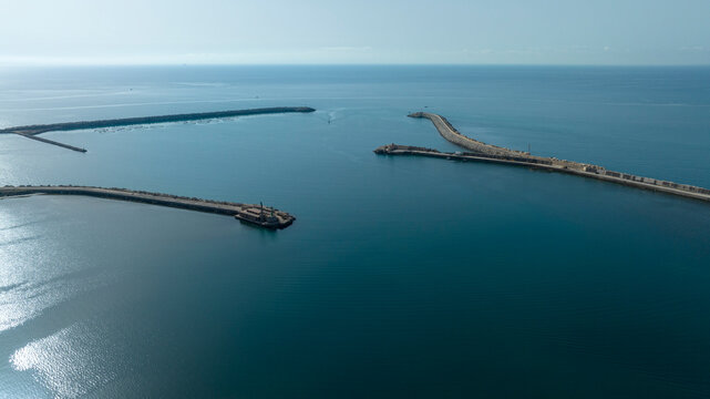 Aerial view of the mouth of a port. The sea extends to the horizon in a backlight. - Powered by Adobe